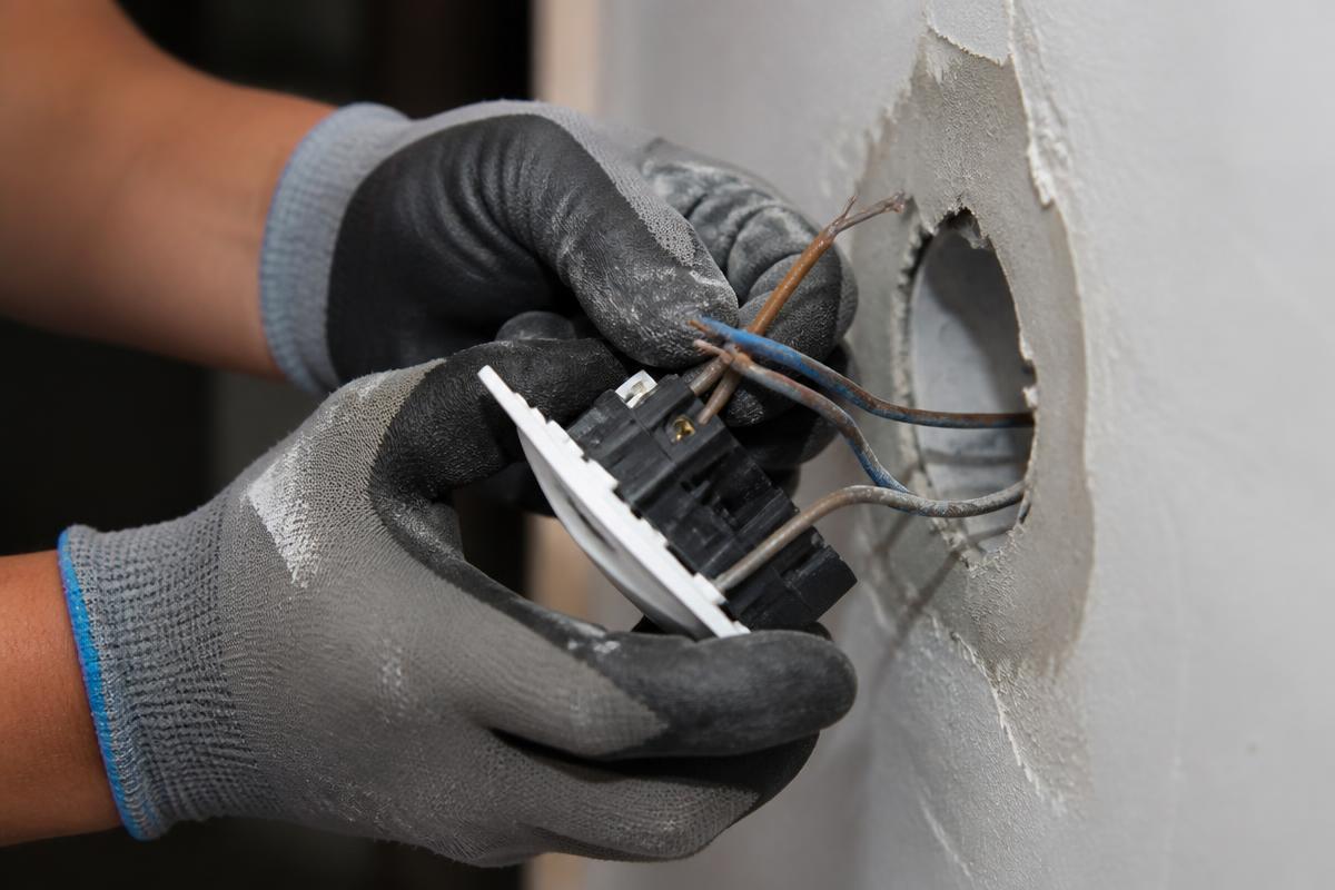Profissional em execução de trabalhos de eletricidade numa cozinha